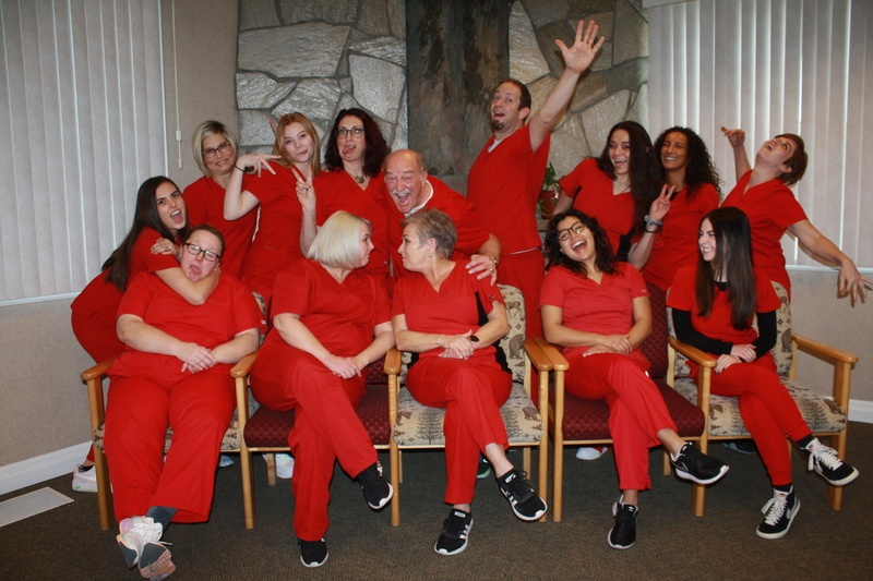 Mirci Dental Team all wearing red scrubs and looking fun